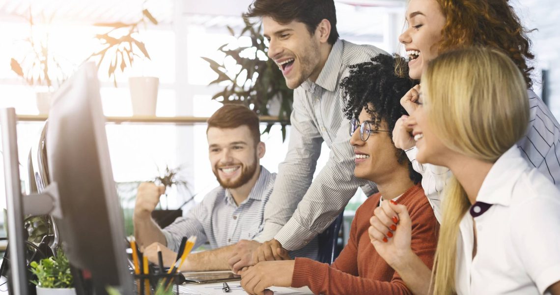Young team of excited coworkers celebrating in office